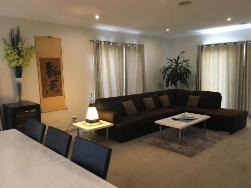 a living room with a black couch and a table at Apple House in Tarneit