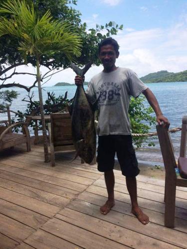 a man holding a fish in his hand on a dock at Palmyra Indah Bungalows in Sekotong