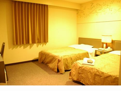 函館市にあるホテルハートインのベッド2台と窓が備わるホテルルームです。