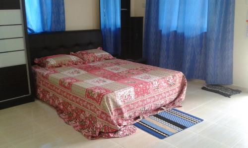 a bedroom with a bed with blue curtains at Homestay Kg Paya D Jitra in Jitra