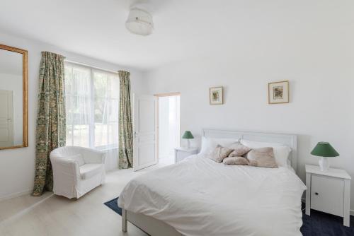 una camera da letto bianca con un letto e una sedia di Le Manoir de la Riviere a Saint-Seurin-de-Prats