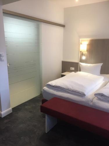 a bedroom with a bed and a door and a red bench at WH Hotels Papenburg Zentrum in Papenburg
