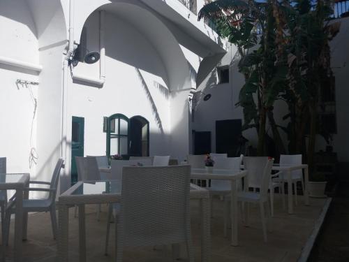 a dining room with white tables and chairs and umbrellas at Antico Palazzo Spinola in Gallipoli