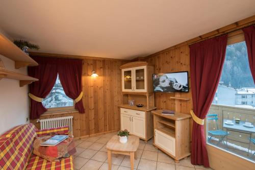 ein Wohnzimmer mit einer Küche mit roten Vorhängen in der Unterkunft Baita Canton in Valfurva