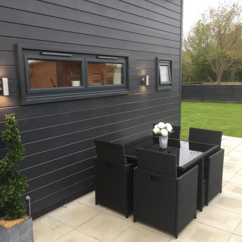 a patio with a table and chairs against a wall at Willow Court Farm Studio West & Petting Farm, 8 mins to Legoland & Windsor, 15 mins to Lapland UK in Windsor