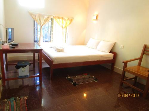 a bedroom with a bed and a desk and a window at Visal Sak Guesthouse in Kep