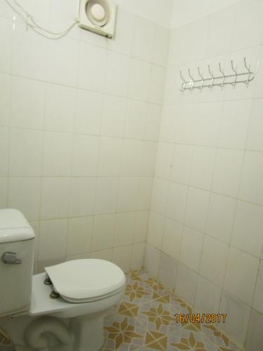 a bathroom with a white toilet and a tiled wall at Visal Sak Guesthouse in Kep