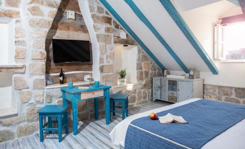 a bedroom with a bed and a table and a tv at Guesthouse Rustico in Dubrovnik