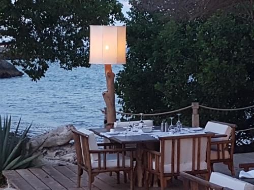 a table with chairs and a lamp on a deck next to the water at The Kasa Malindi in Malindi