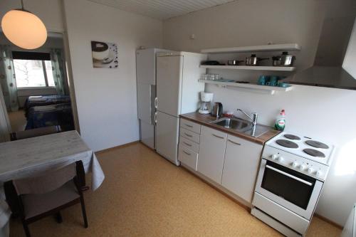 a small kitchen with a white refrigerator and a table at Economy Apartments Peura in Rovaniemi
