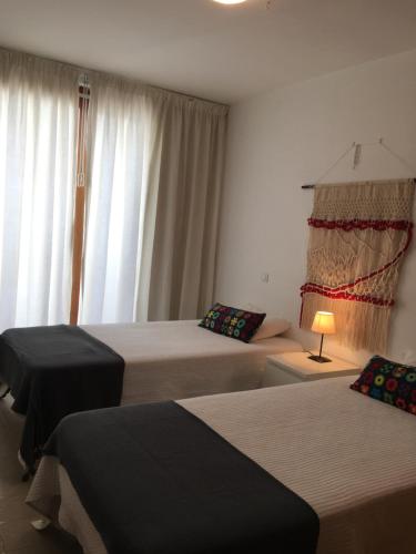 a hotel room with two beds and a window at Monte Gordo Flat in Monte Gordo