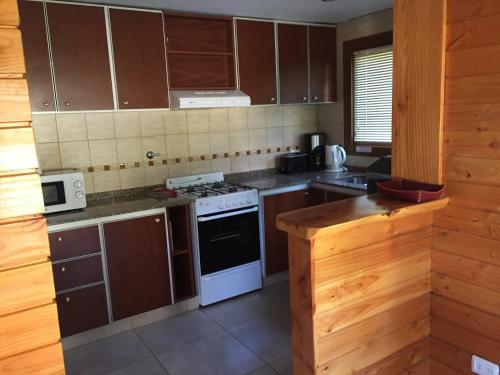 a kitchen with wooden cabinets and a white stove top oven at Encanto del Rio in Villa La Angostura