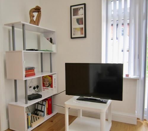 a living room with a tv and a white table at Temeside Garden House in Ludlow