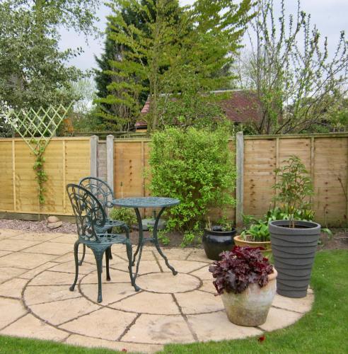 a patio with a table and chairs and potted plants at Temeside Garden House in Ludlow