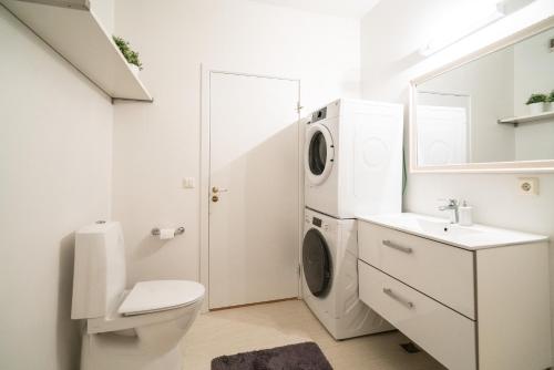 a white bathroom with a washing machine and a sink at River Apartments in Selfoss