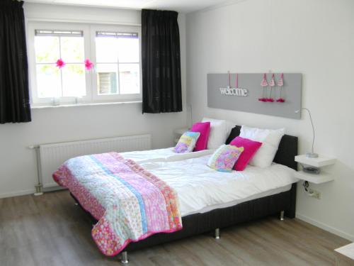 a bedroom with a large bed with pink and purple pillows at De Beddestee in Ruinen