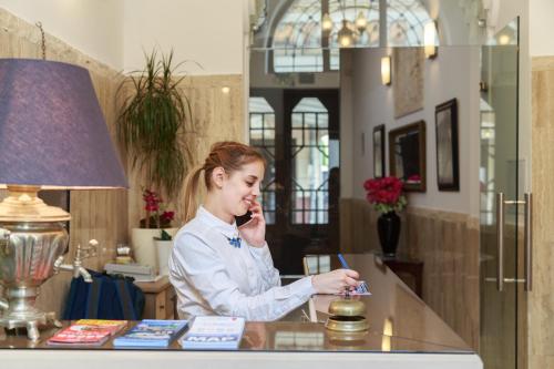 a woman sitting at a desk talking on a cell phone at Hotel Mika Downtown in Budapest