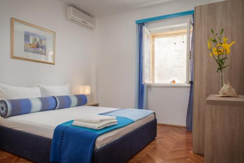 Apartments Potts Point في ماكارسكا: غرفة نوم بسرير وملاءات زرقاء ونافذة