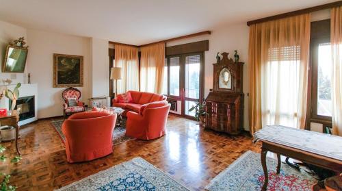a living room with orange chairs and a clock at Villa Tra' Monti in Bassano del Grappa