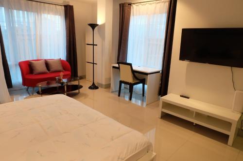 ein Schlafzimmer mit einem Bett, einem Fernseher und einem Stuhl in der Unterkunft DewyHouse in Chiang Mai