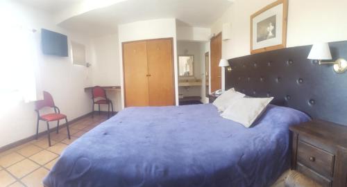 a bedroom with a large blue bed and two chairs at Montecassino in Capilla del Monte