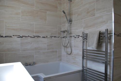 a bathroom with a shower and a tub and a sink at Mornant Cottage in Prestatyn