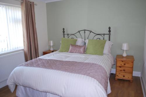 a bedroom with a large bed with white sheets and green pillows at Mornant Cottage in Prestatyn