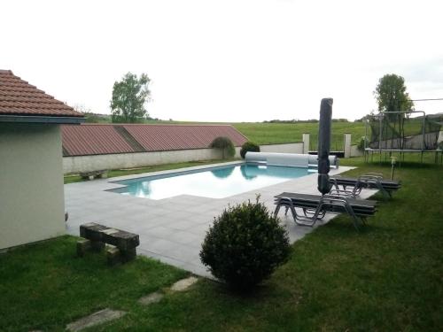 a swimming pool in a yard with two chairs and a bench at Les Petunias in Hugier