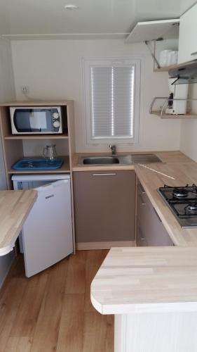 une petite cuisine avec une cuisinière et un micro-ondes dans l'établissement Camping de la minière, à Forges-les-Eaux