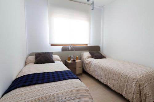 プレヤス・デ・オリフエラにあるCabo Roig Terrazas de Campoamor 25の白い壁の客室で、ベッド2台、窓が備わります。