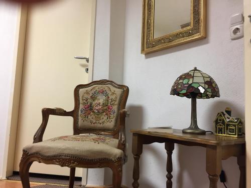 a chair sitting next to a table with a lamp at Apartment Una - Self check in in Graz