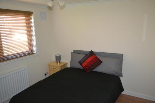 a bedroom with a bed with a black blanket and a window at Wick Apartment in Wick
