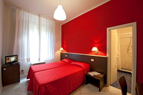 a red bedroom with a red bed and a window at Hotel Moderno in Siena