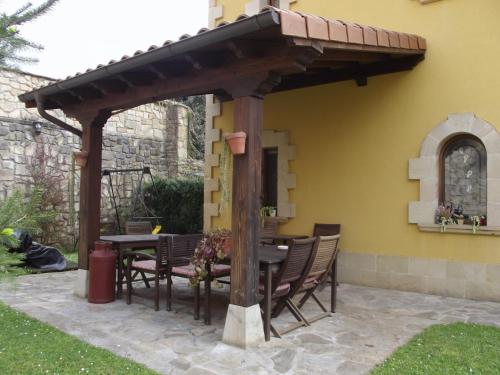 a wooden pergola with a table and chairs on a patio at Posada Carpe Diem in Liérganes