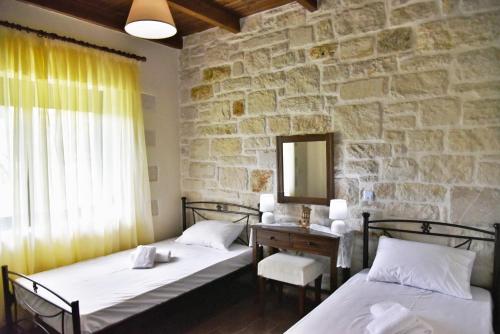 2 camas en una habitación con una pared de piedra en Little House on the Prairie - Chania en Katokhórion