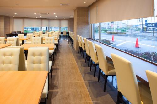 a dining room with tables and chairs and a large window at Hotel Aston Plaza Kansai Airport in Izumi-Sano