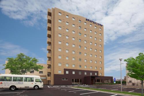 a white bus parked in front of a building at Hotel Aston Plaza Kansai Airport in Izumi-Sano