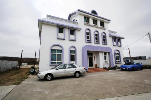 a white house with a car parked in front of it at 驫風民宿 Equuleus Homestay in Magong