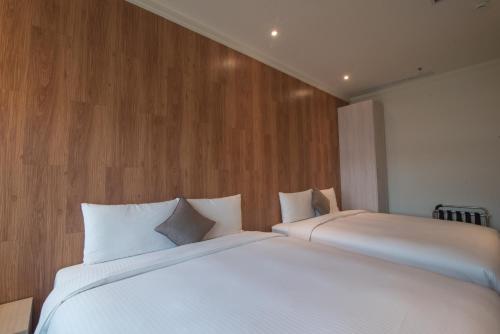 two beds in a bedroom with wooden walls at Merryday Hotel Banqiao in Taipei