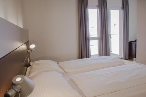 a bedroom with a white bedspread and white pillows at Hotel Schwarzer Bär in Linz