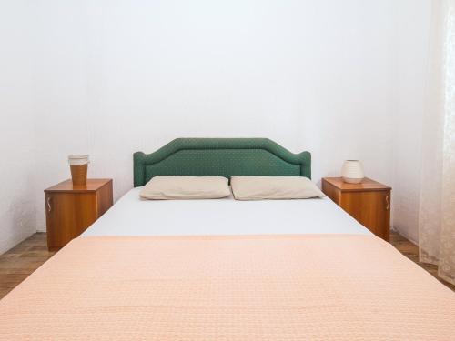 een bed met een groen hoofdeinde en twee nachtkastjes bij Apartment Mile in Petrovac na Moru