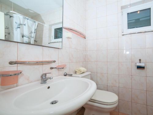 een badkamer met een wastafel, een toilet en een spiegel bij Apartment Mile in Petrovac na Moru