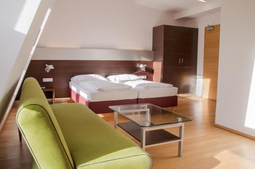 a bedroom with a bed and a couch and a table at Hotel Schwarzer Bär in Linz