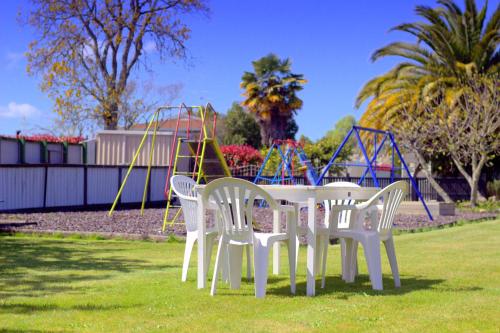 a table and chairs in a park with a playground at Motueka Garden Motel in Motueka