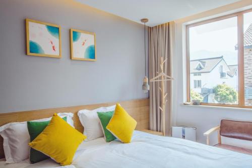 a bedroom with a bed with yellow and green pillows at Han Xuan Boutique Hostel in Hangzhou