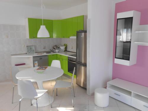 een keuken met groene kasten en een witte tafel en stoelen bij Apartman Gabi in Kastav
