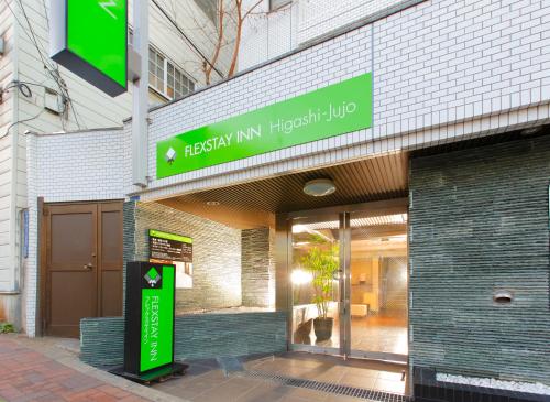 a green building with a sign on the side of the building at FLEXSTAY INN Higashi Jujo in Tokyo