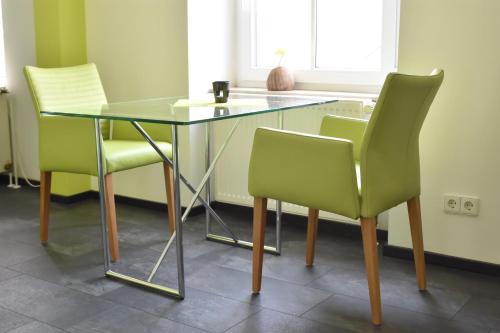 a glass table and two green chairs in a room at Landhotel Gillenfelder Hof in Gillenfeld