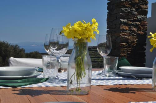 een tafel met glazen en een vaas met gele bloemen erin bij House On the Ancient Footpath in Faros