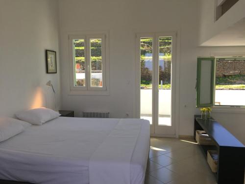 een slaapkamer met een wit bed en 2 ramen bij House On the Ancient Footpath in Faros